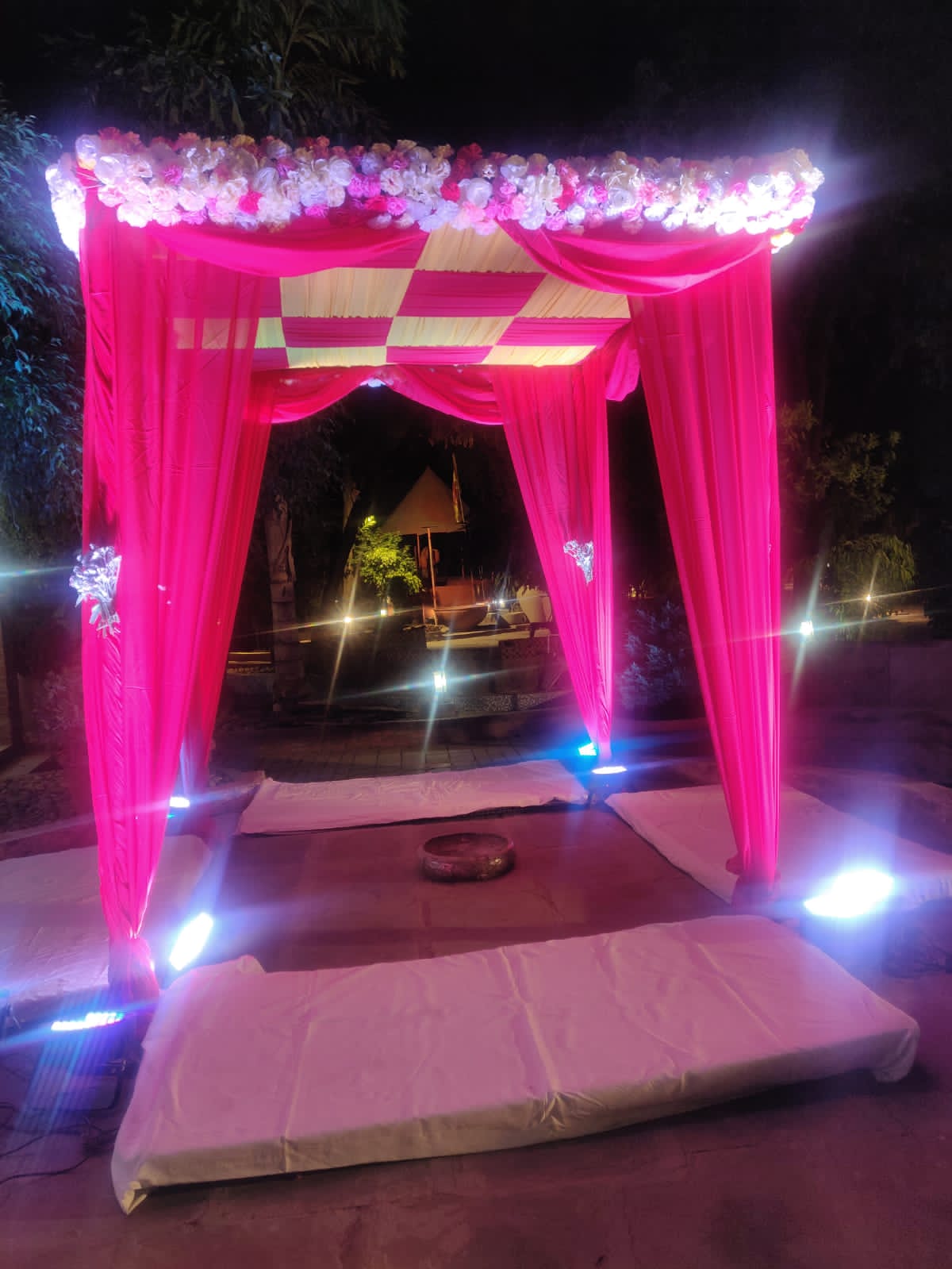 Sacred twilight mandap adorned with cascading pink and ivory carnation garlands and hand-carved pillars