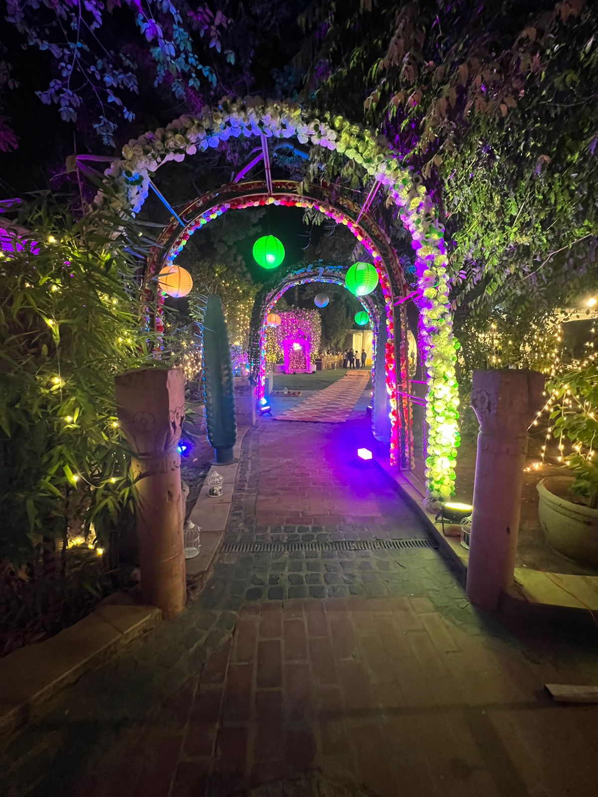 Opulent floral arched pathway flanked by glowing warm paper lanterns