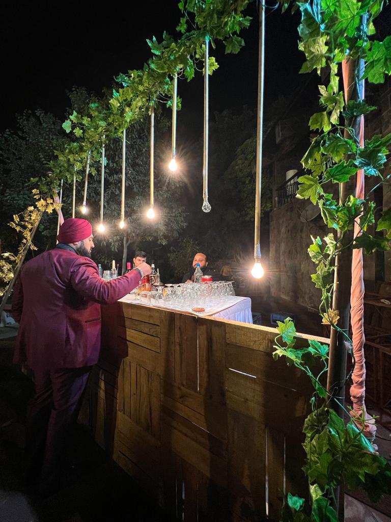 Handcrafted rustic timber cocktail bar illuminated with suspended warm Edison filament bulbs