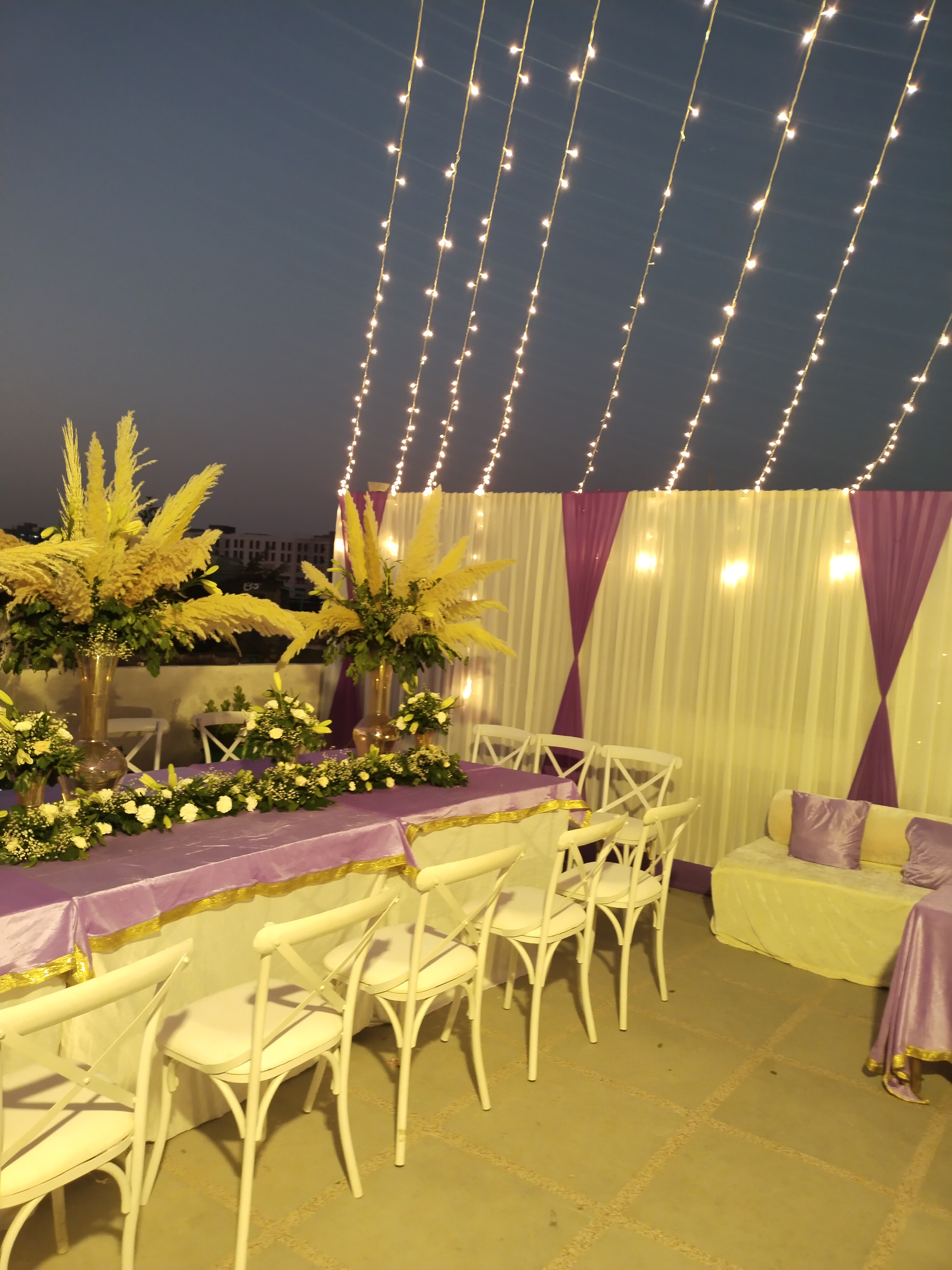 Twilight panoramic rooftop reception with illuminated tented canopy and warm mood lighting
