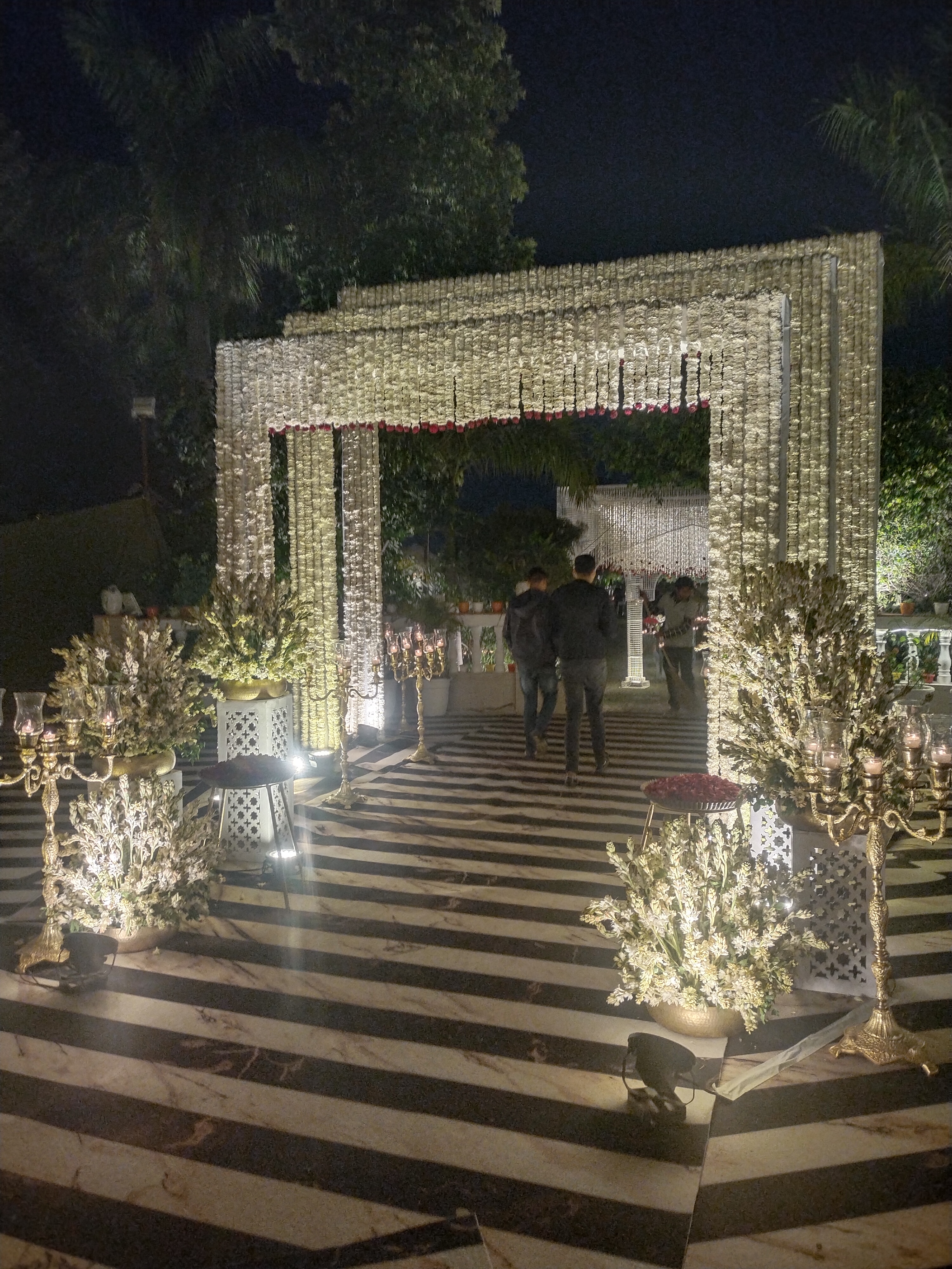 Monolithic portal arch lined with thousands of white tuberose garlands and brass candelabras