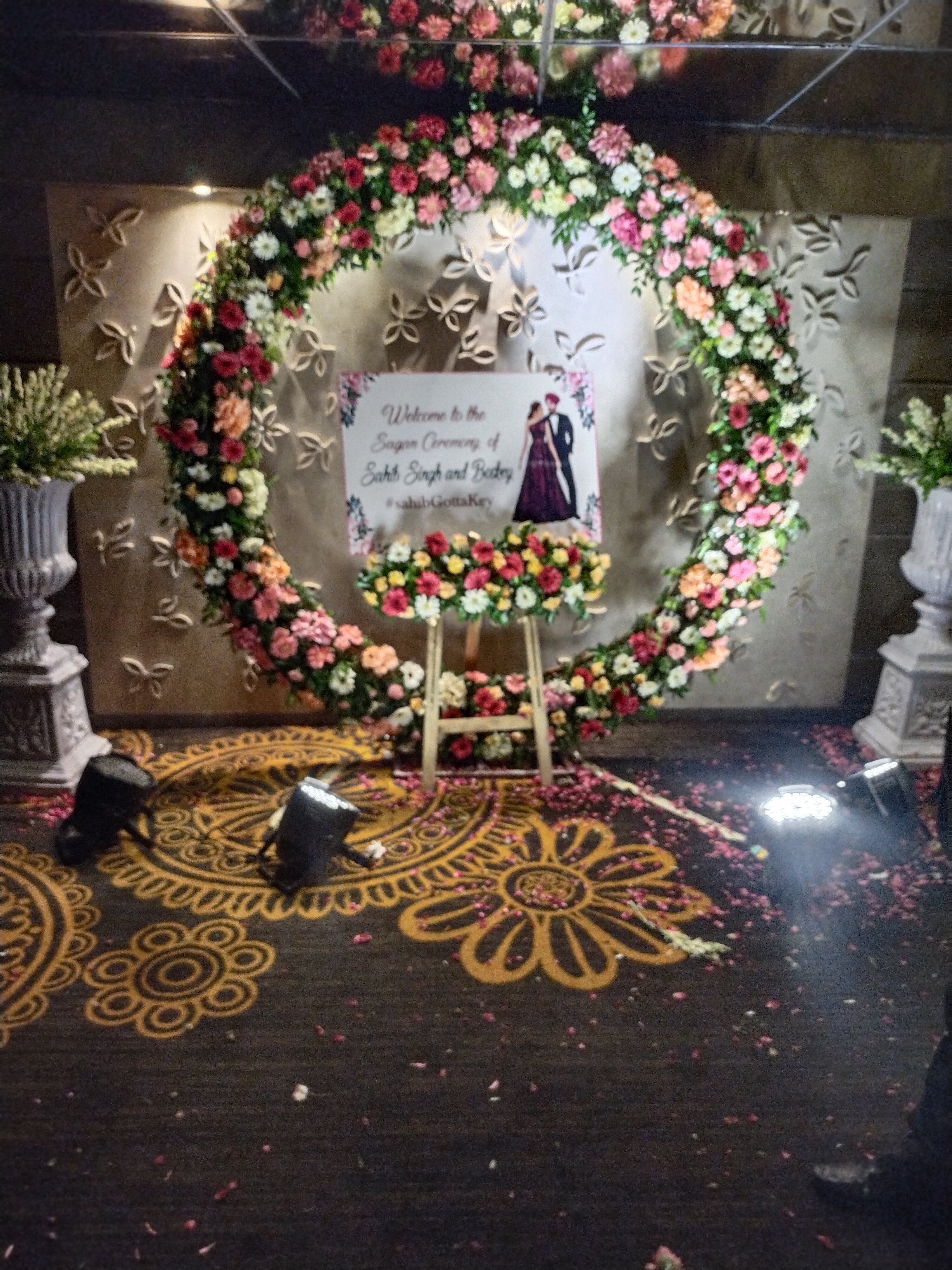 Circular floral wreath welcome installation for Sagan ceremony with Roman stone urns
