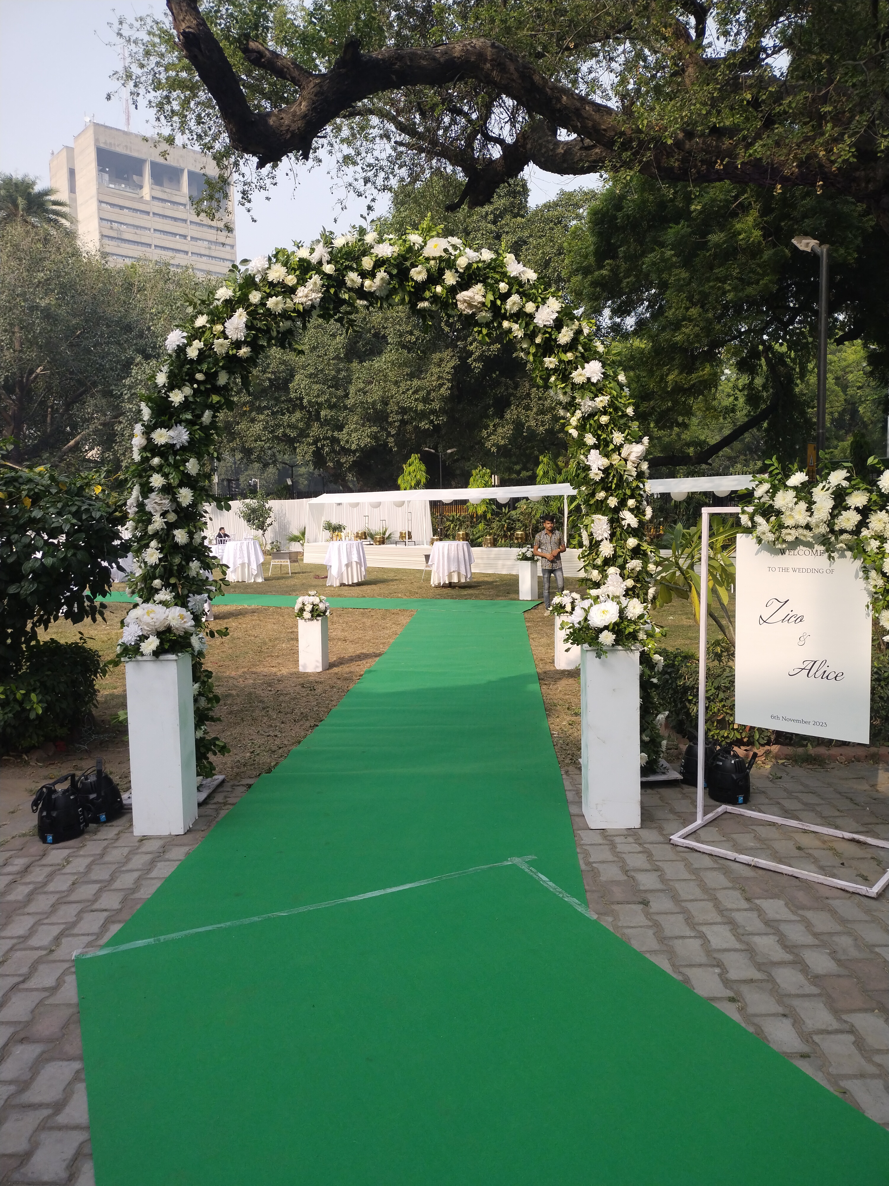Lush botanical garden setting with fresh white floral arch and emerald green runner carpet